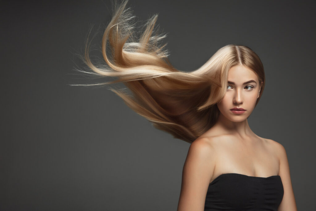 beautiful-model-with-long-smooth-flying-blonde-hair-isolated-on-dark-grey-studio-background-young-caucasian-model-with-well-kept-skin-and-hair-blowing-on-air